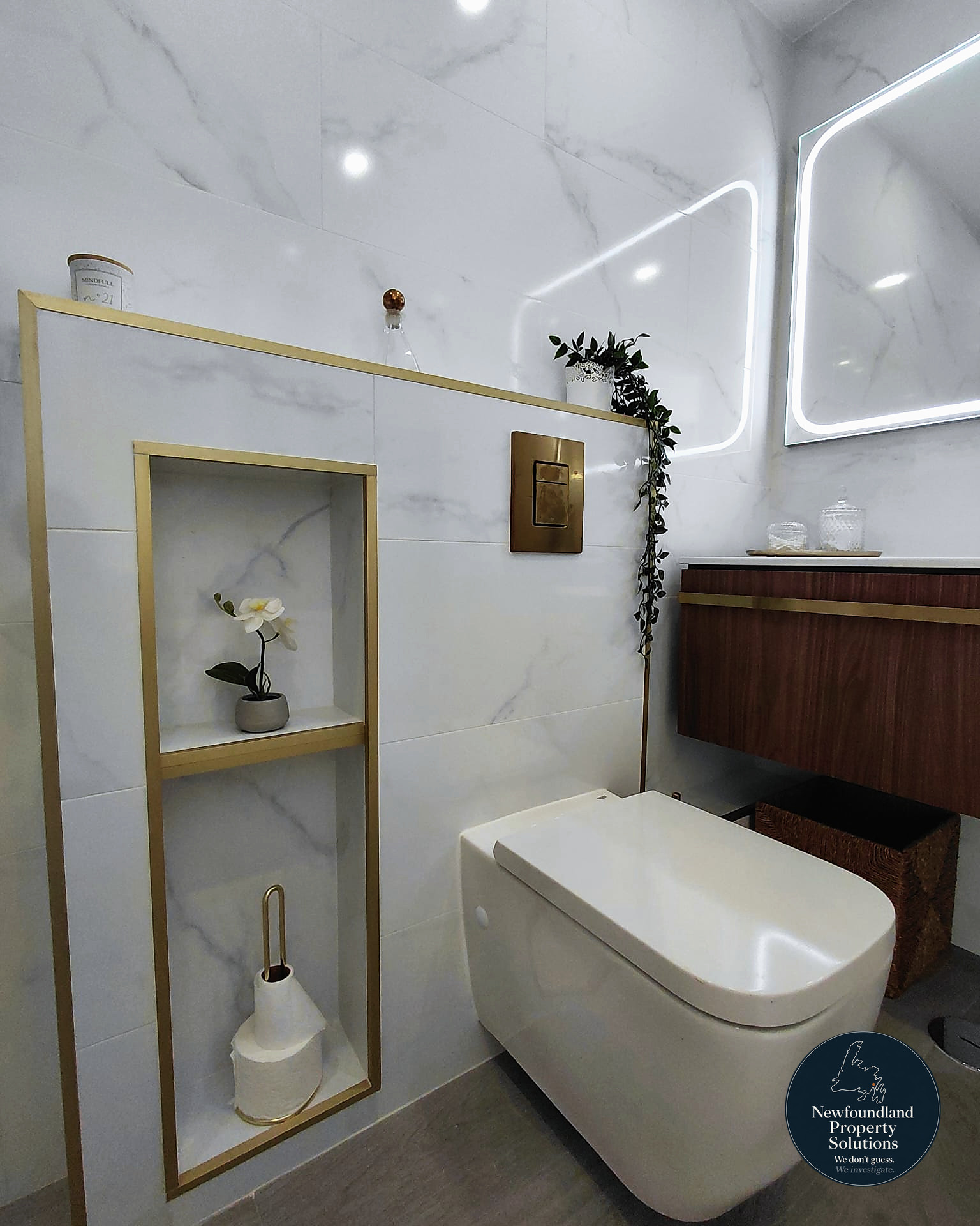 Recessed brass-framed niche beside wall-hung WC